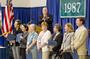 Dean of the Faculty Roger Brooks, background, applauds professors celebrating milestone anniversaries at Alumni Convocation. From left: Blanche Boyd and Julie Rivkin, 30 years; Joan Chrisler and Kathleen McKeon, 25 years; and MaryAnne Borrelli, Leslie Brown and T. Page Owen, 20 years.