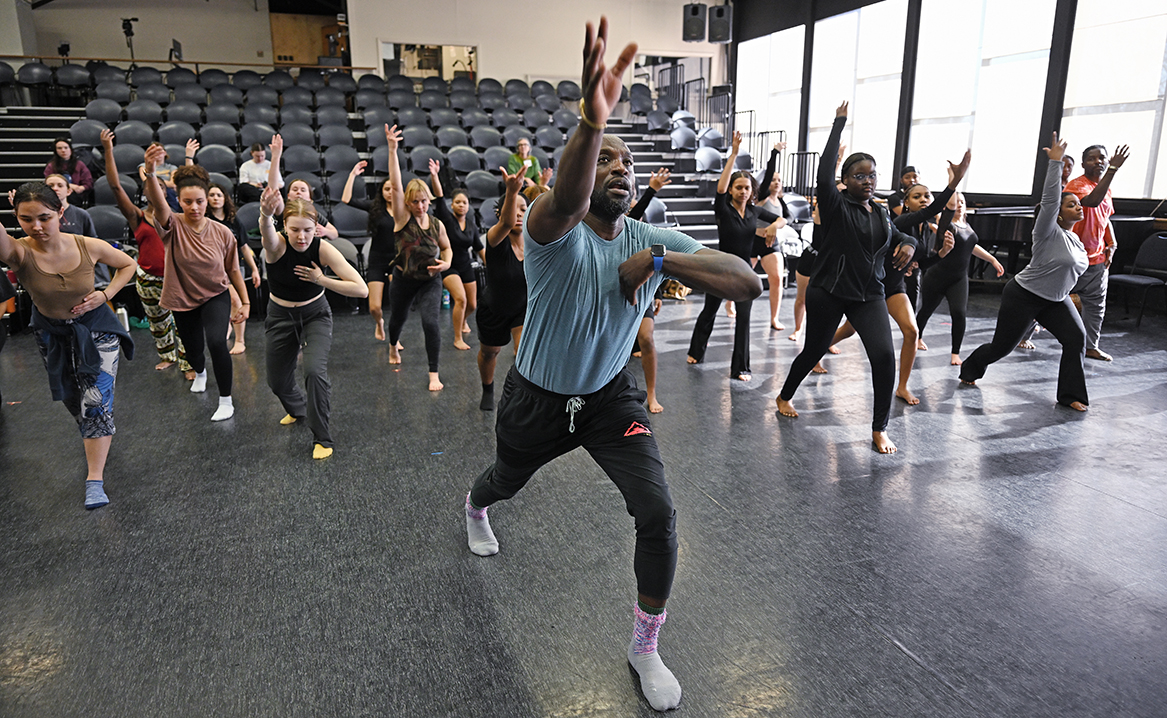 Dance teacher leads large class in studio