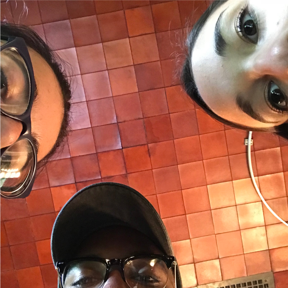 The eyes and foreheads of three students peer into the camera lens with copper ceiling above.