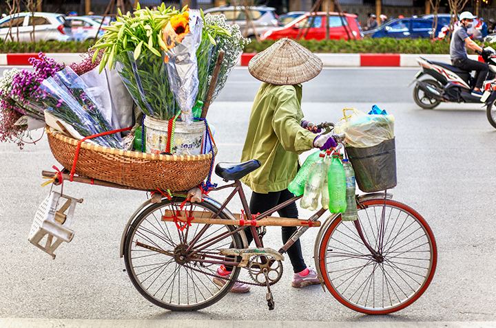 Woman on bicycle with flowers in a basket