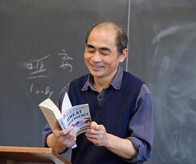 John Qunjian Tian, professor of government and international relations, reads a passage from a book to his class.