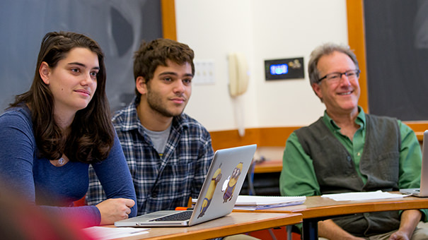 Philosophy students and professor Larry Vogel listen attentively to a speaker in the classroom.