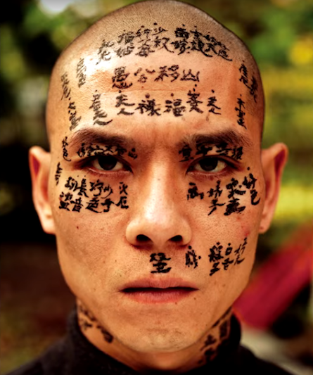 A tattooed face of a figure from the film Chinese Lives of Uli Sigg