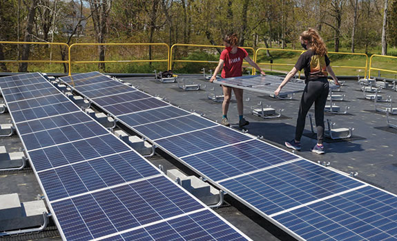 Two students carrying solar panels
