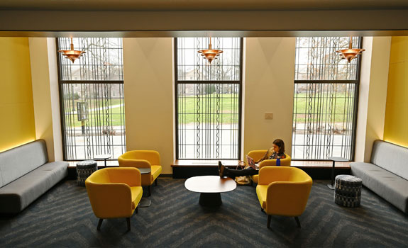 A student studying in the Athey Center, sitting in a yellow chair