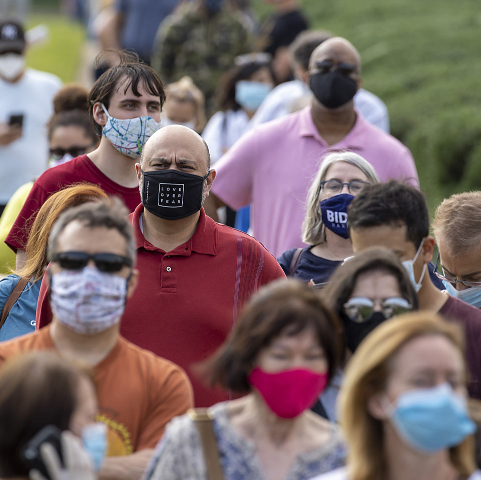 Image of people waiting in line to vote wearing masks