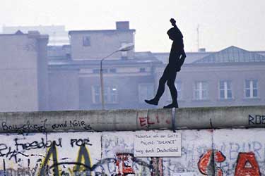 Figure walking on graffitied wall, stray dog nearby