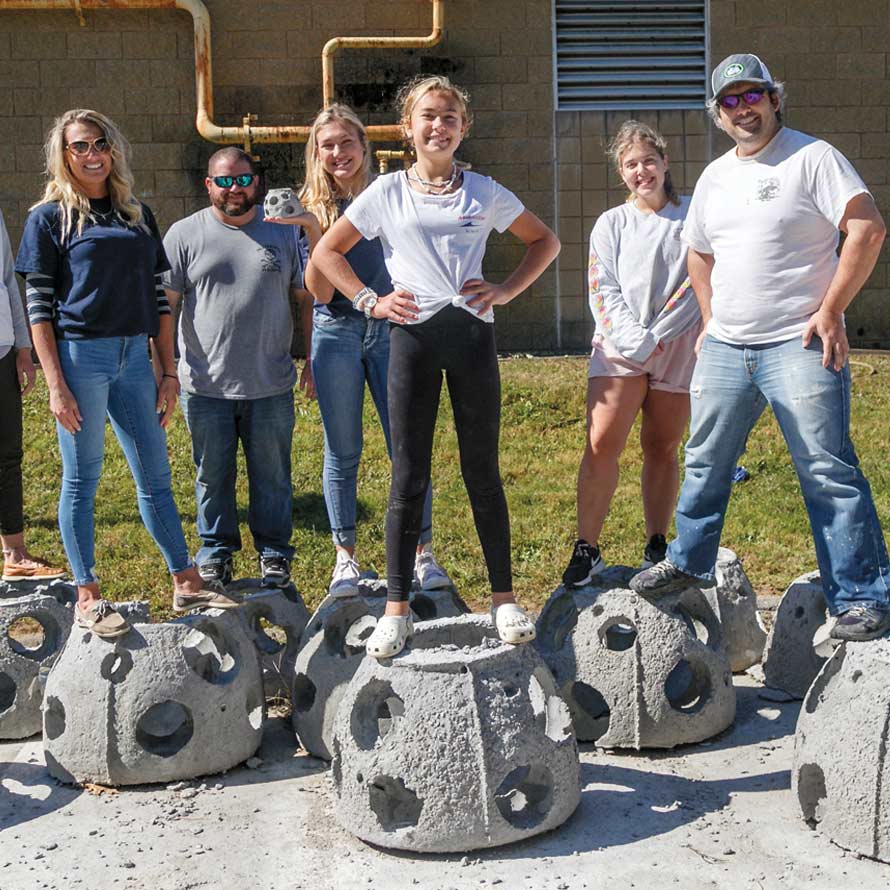 Photo of students standing atop concrete reef balls