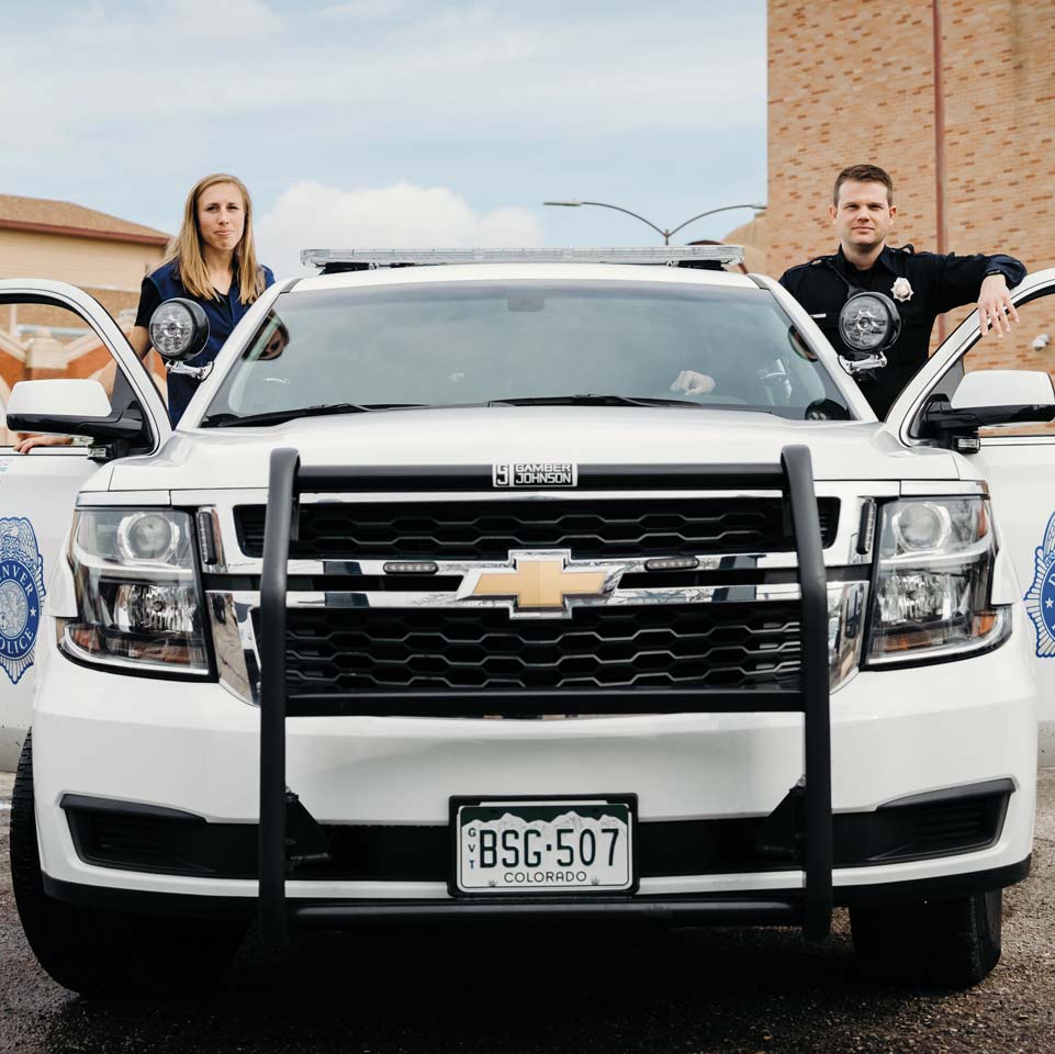Image of Kathy Evans ’14 and a police officer standing by a patrol car