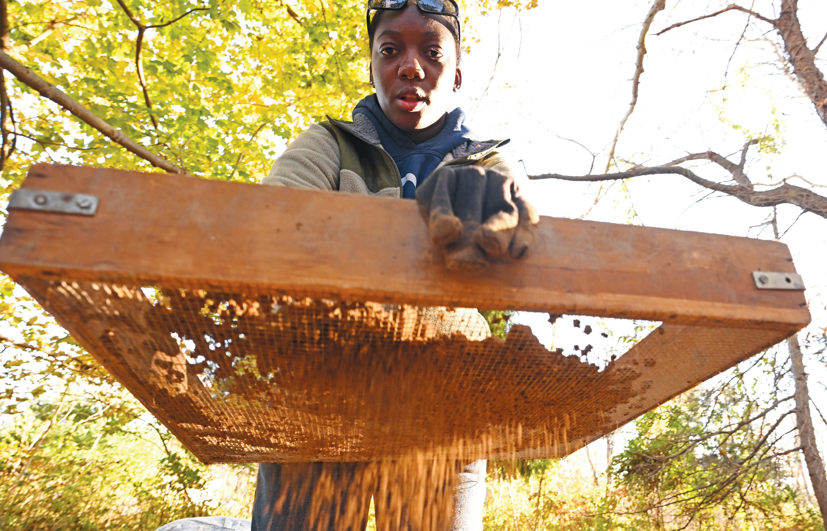 Francis Sesenaya ’24 sifts soil from a test pit during an archeological site survey.