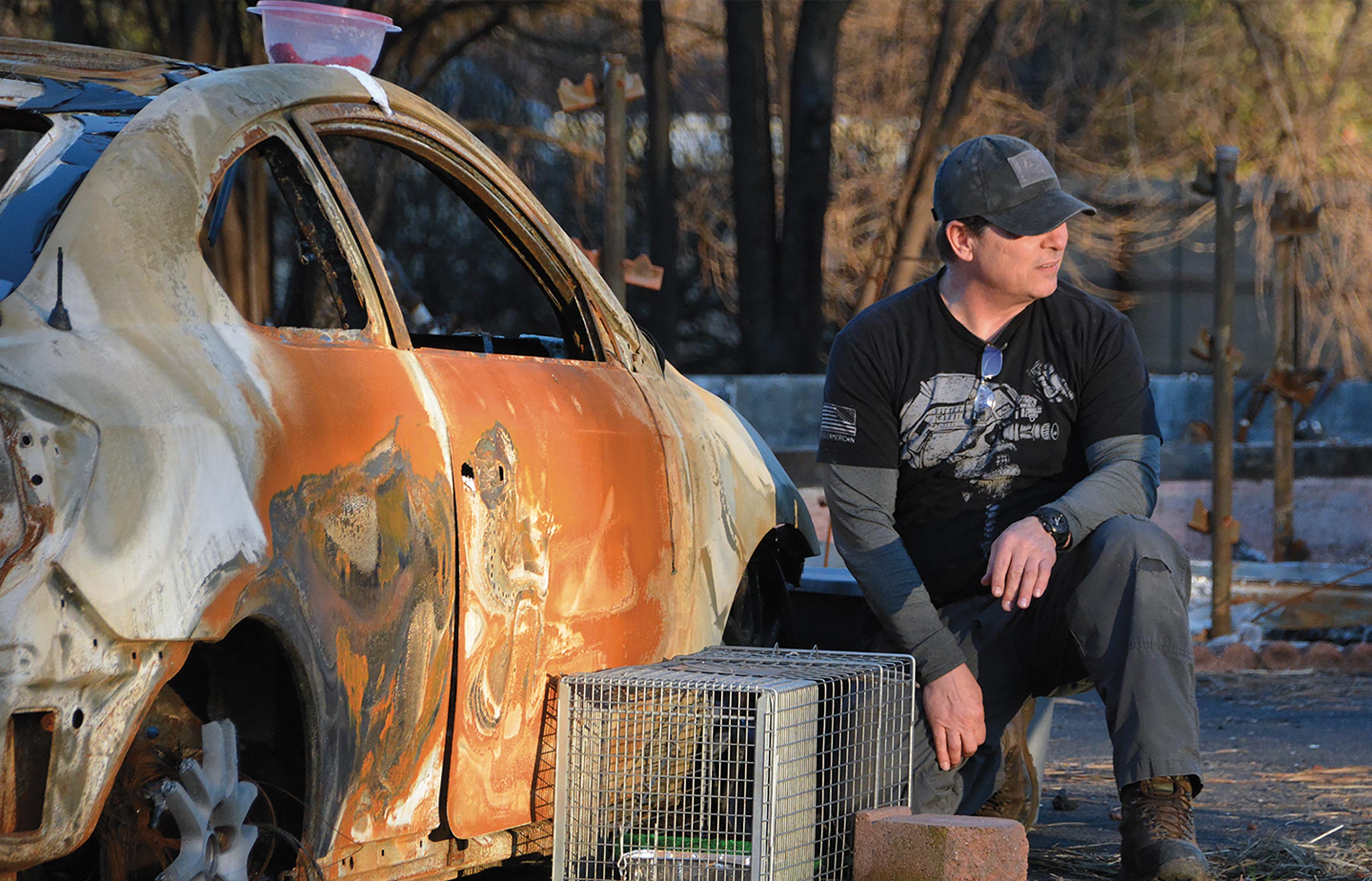 Man next to burnt out car in forest