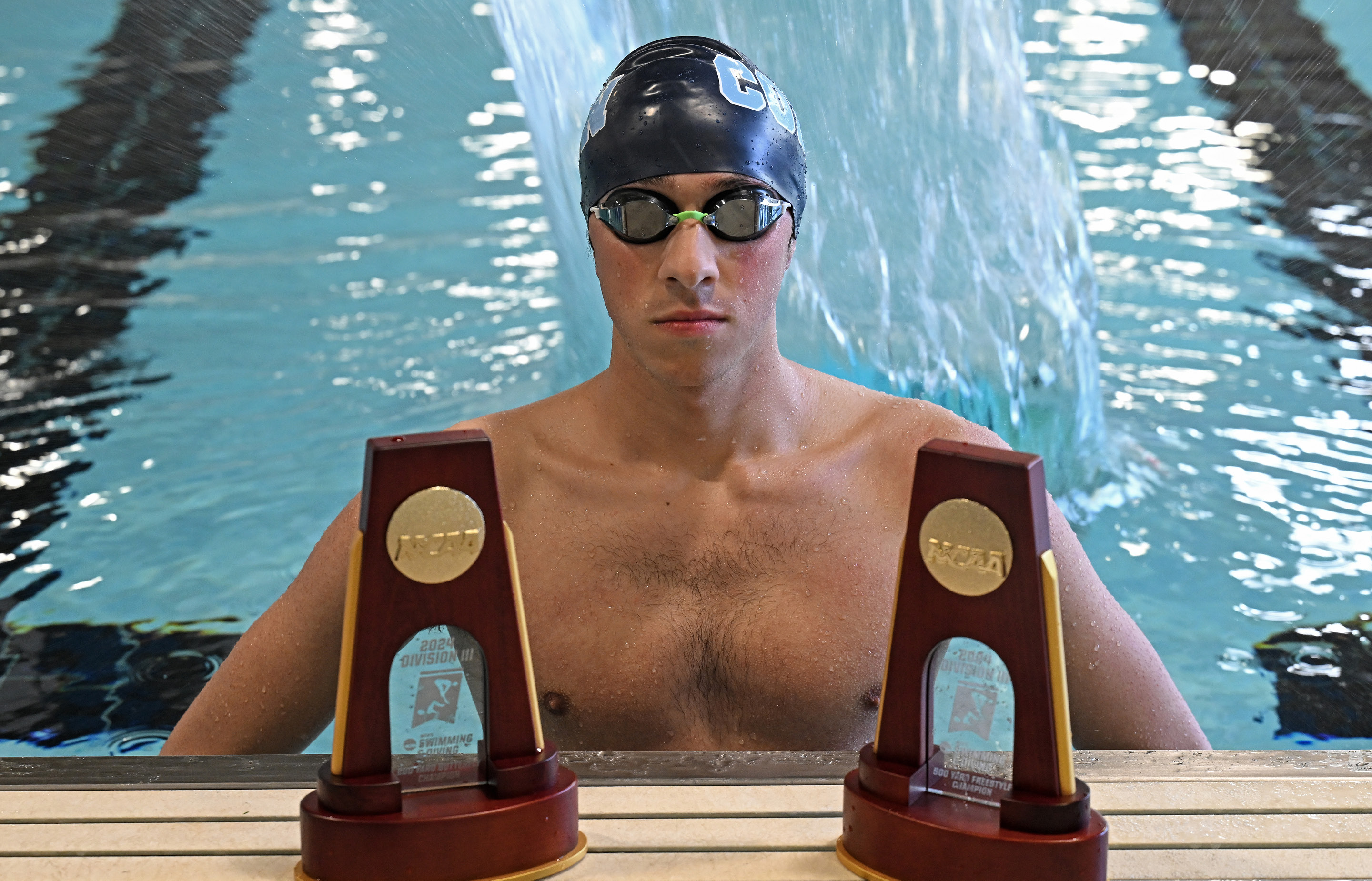 Justin Finkel '25 poses in the pool with trophies.