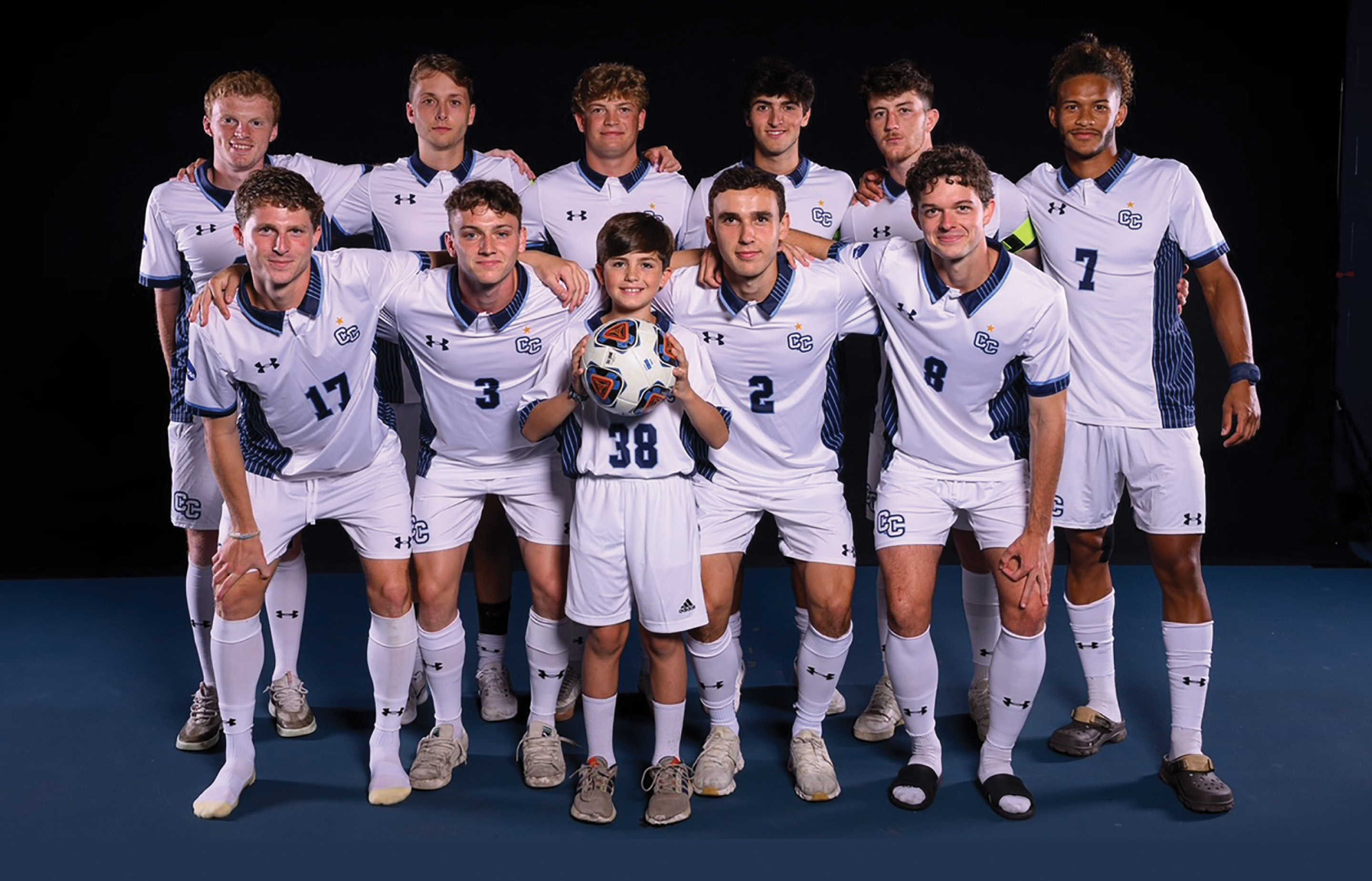 The men's soccer team poses with honorary member Landon Pereira, age 11.
