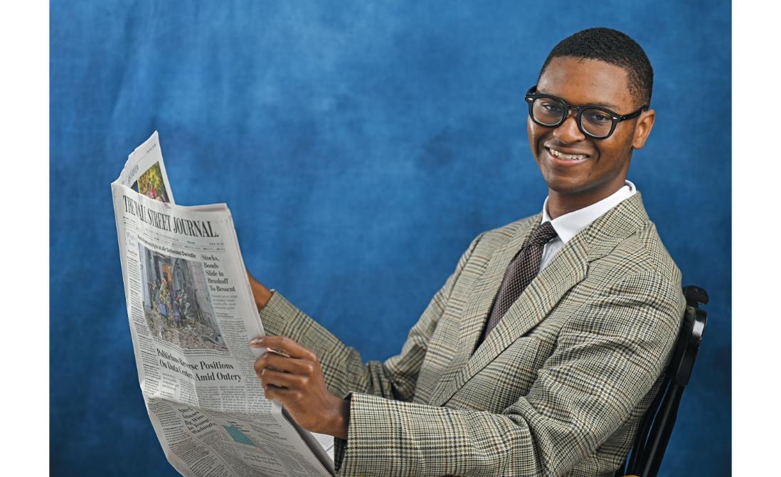 Terell Wright ’25 poses with a newspaper in the studio. Photo by Sean D. Elliot.