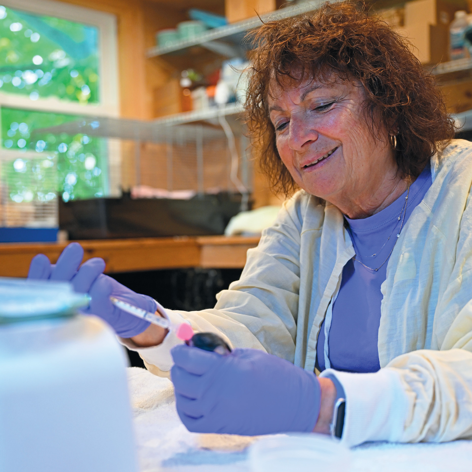 Patty Reilly ’75 in a lab coat feeding a baby rabbit