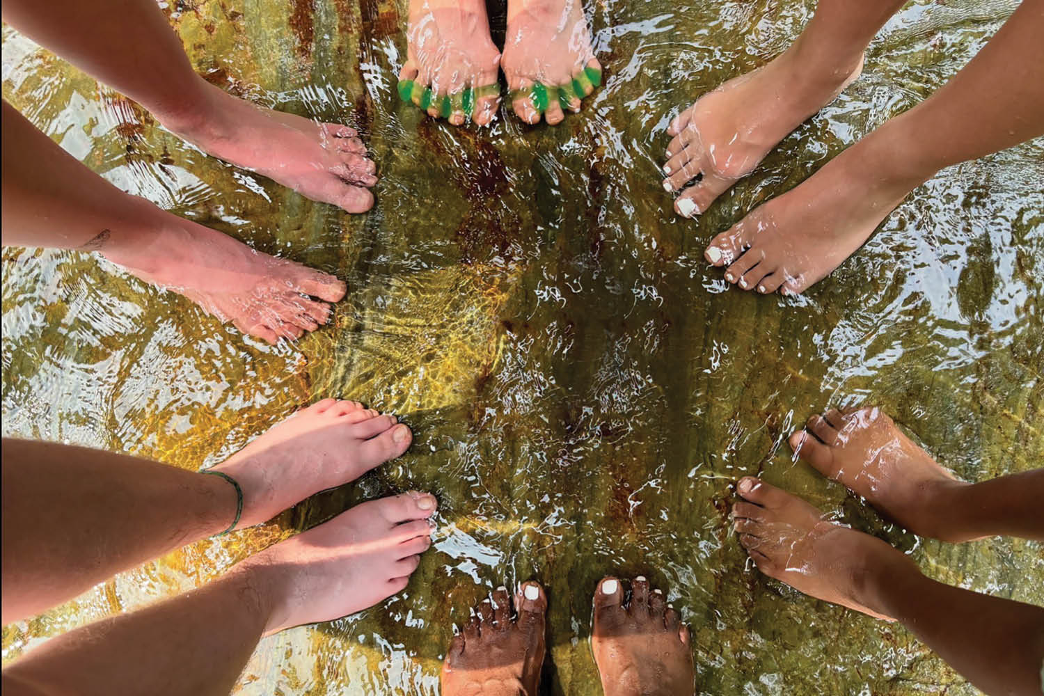 Top-down shot of a bunch of pairs of feet wading in the water