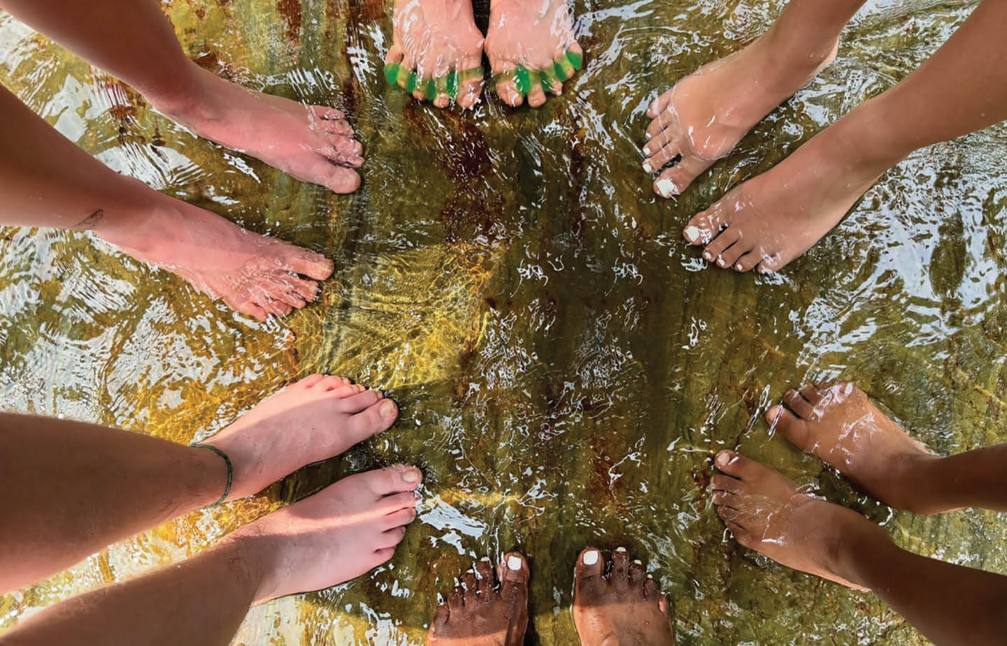 Top-down shot of a bunch of pairs of feet wading in the water