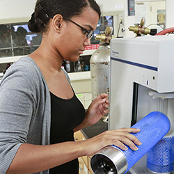 Science Leader Chrismary De La Cruz '16 works in the lab of Kelly Professor of Chemistry Stanton Ching. She is supplying liquid nitrogen to an instrument that measures the surface area of materials.