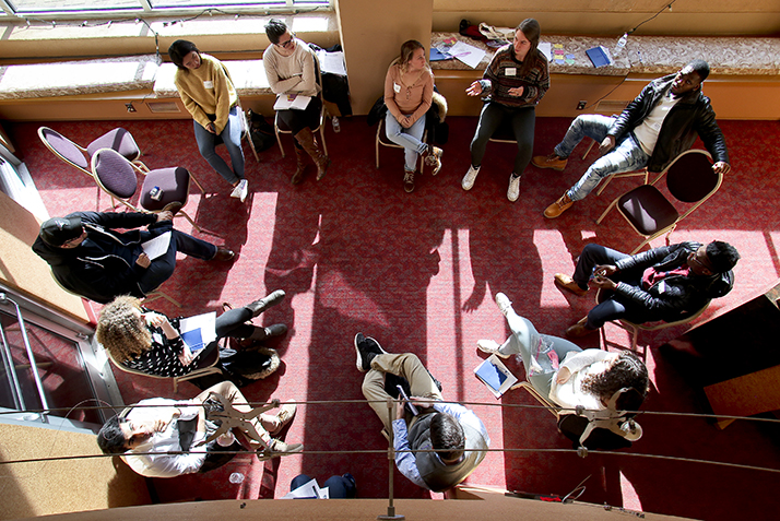 Students sit in a circle having a discussion in this photo, which is shot from above. 