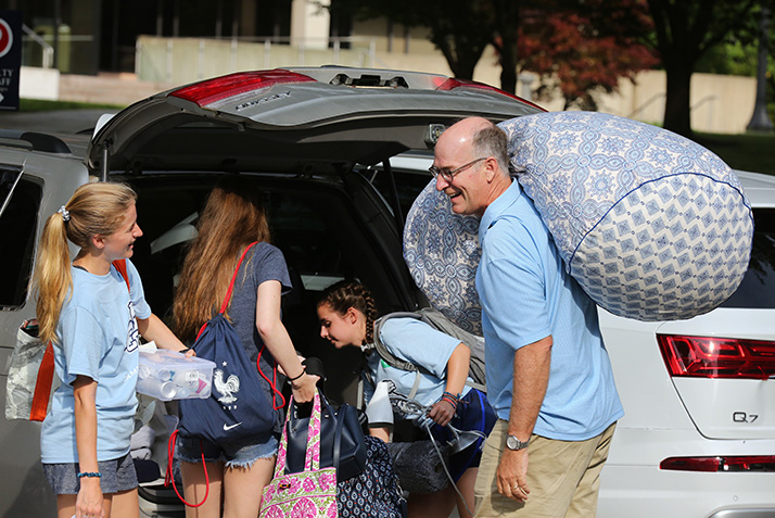 Parents and students unload a van.