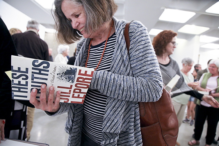 A woman thumbs through a copy of Lepore's latest book, 