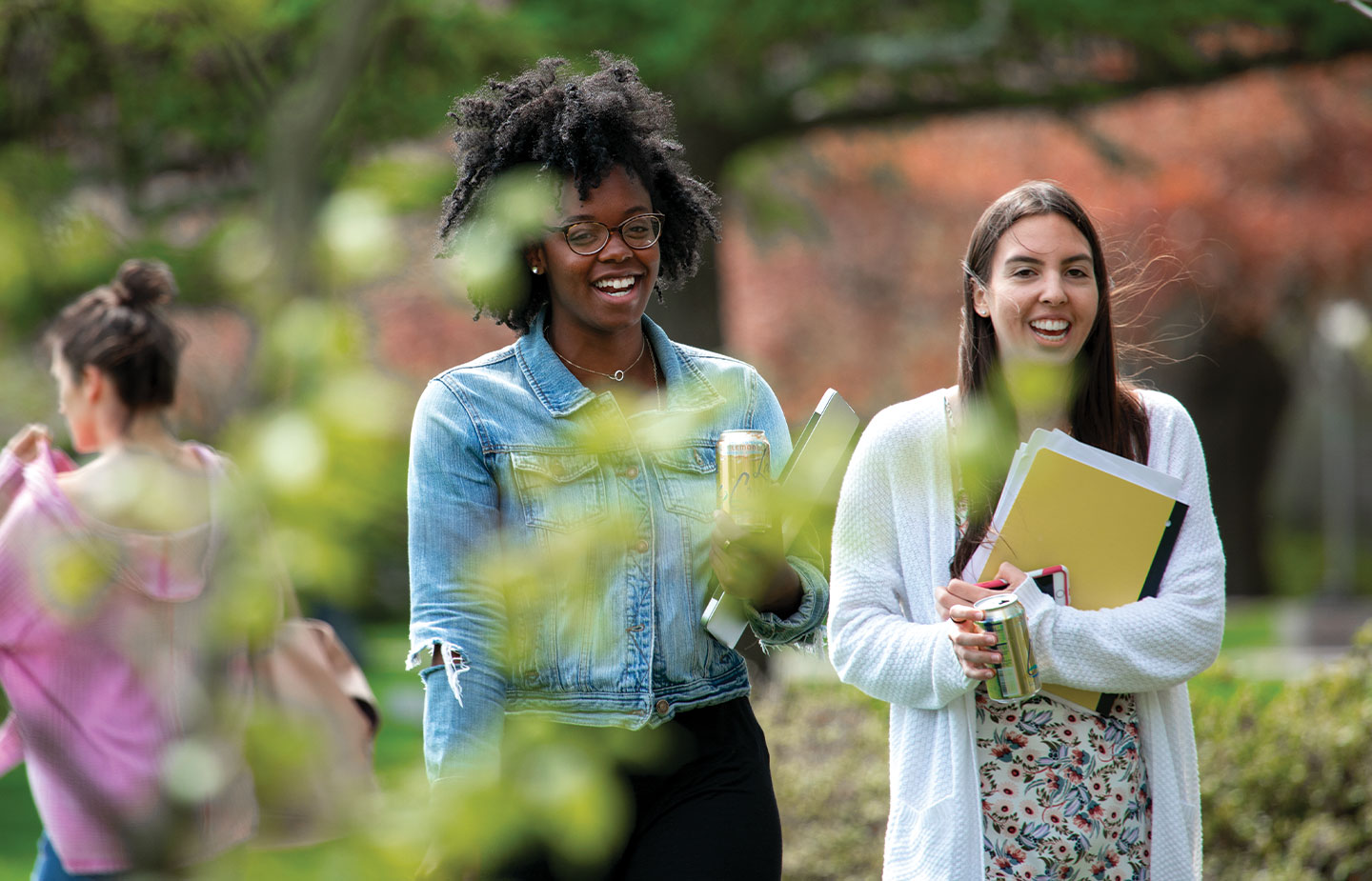 Two female students smiling and walking on campus