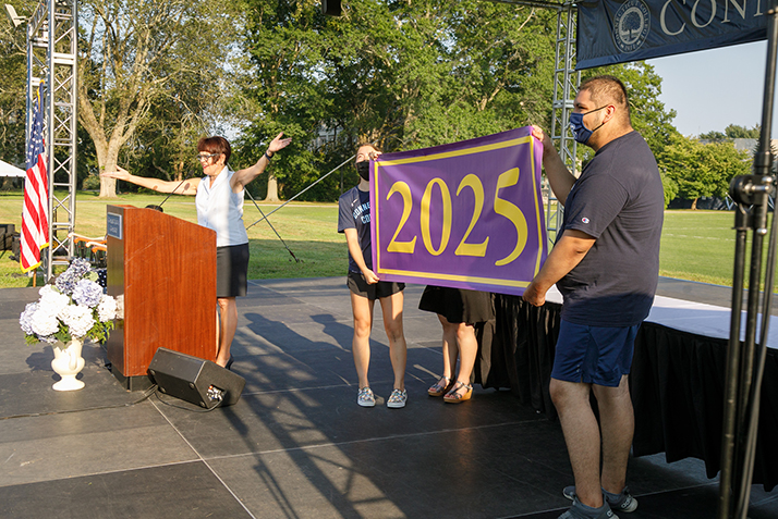 President Katherine Bergeron and two members of the class unveil the Class of 2025 banner. 