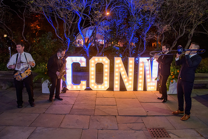 The band plays by a lit Conn sign.