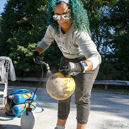 Professor Maria Rosa sprays sugar water on a tetherball that will be used to create a void in a large reef ball.