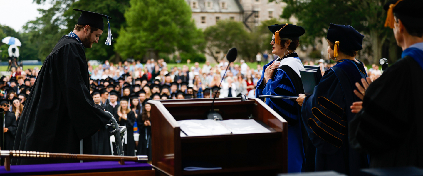 A graduate crosses the stage as President Katherine Bergeron looks on.