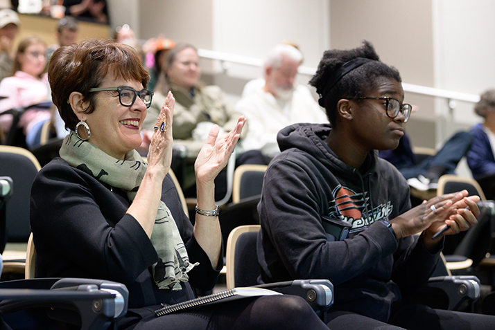 President Katherine Bergeron applauds during a Symposium presentation.