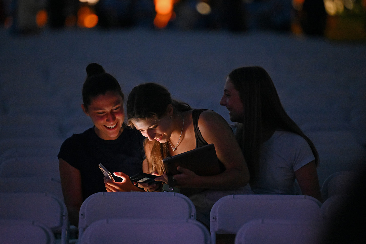 Three students in the dark looking at a cell phone
