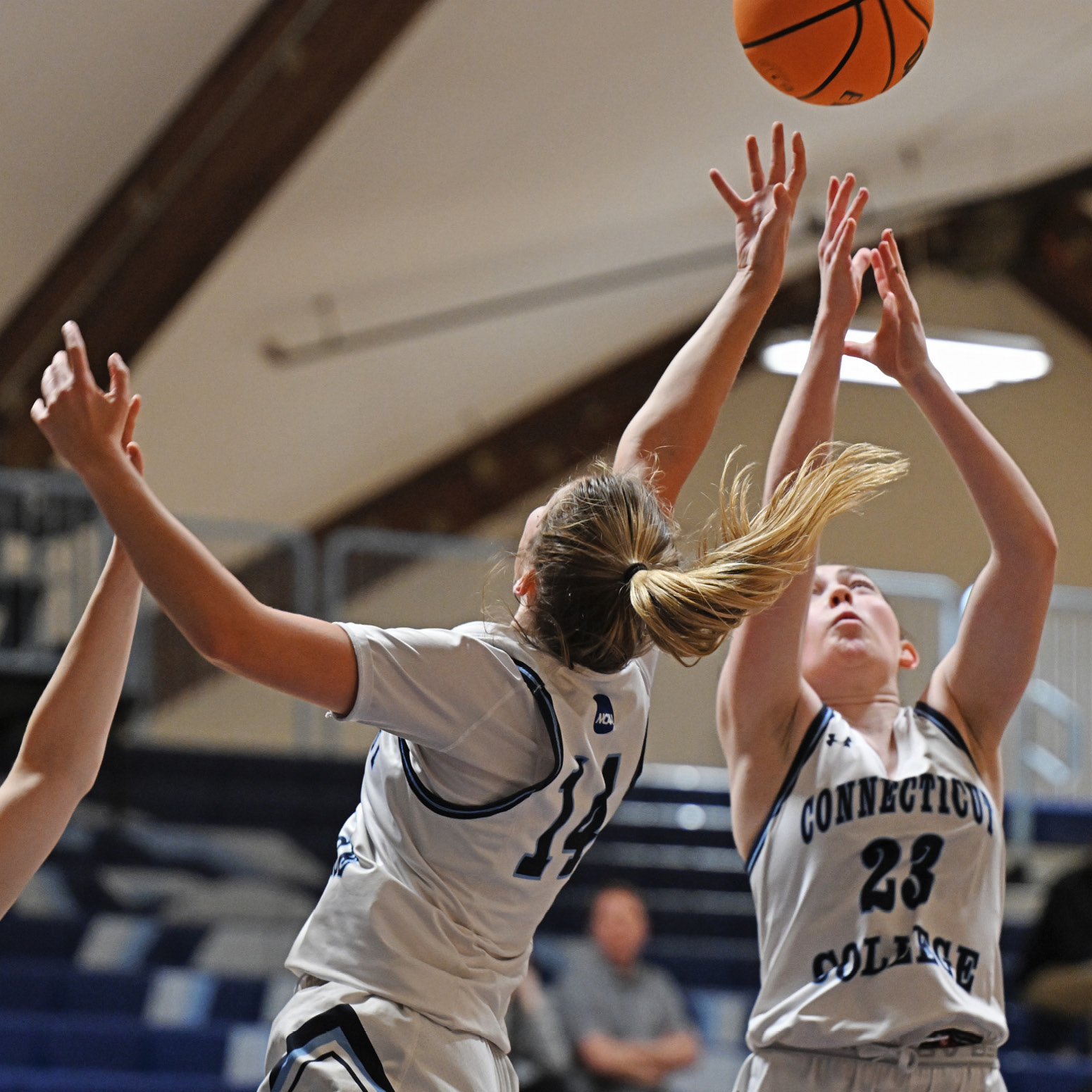 Two women's basketball players jump for a rebound