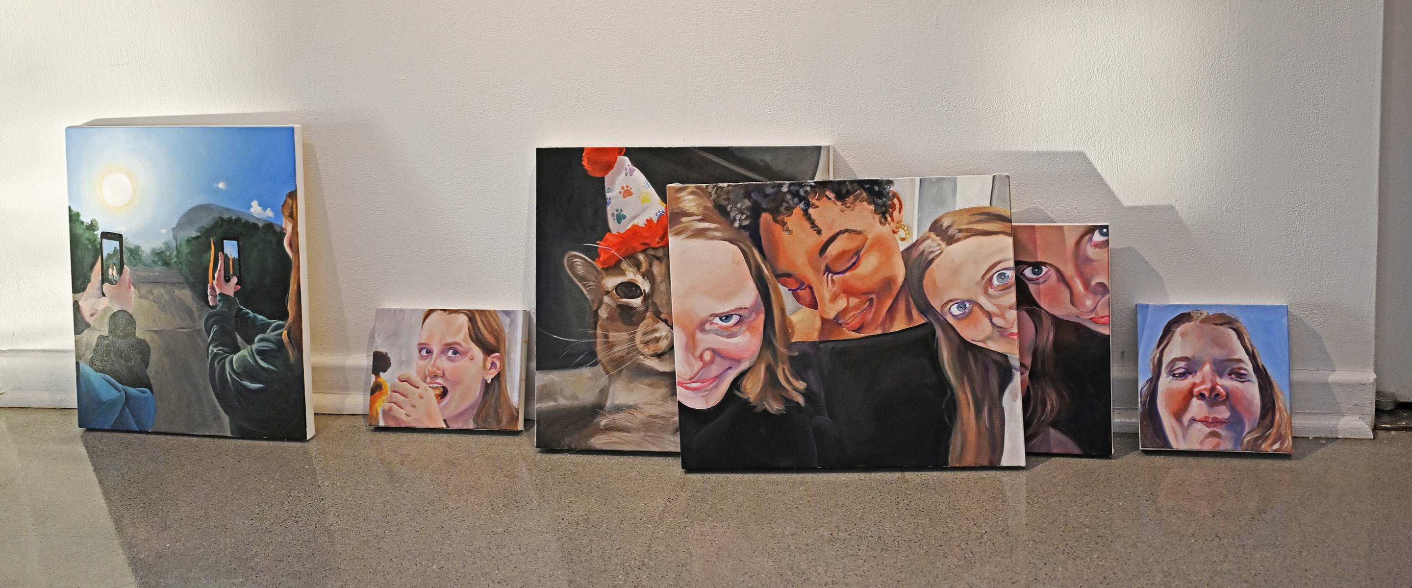 A row of paintings leaning against a wall