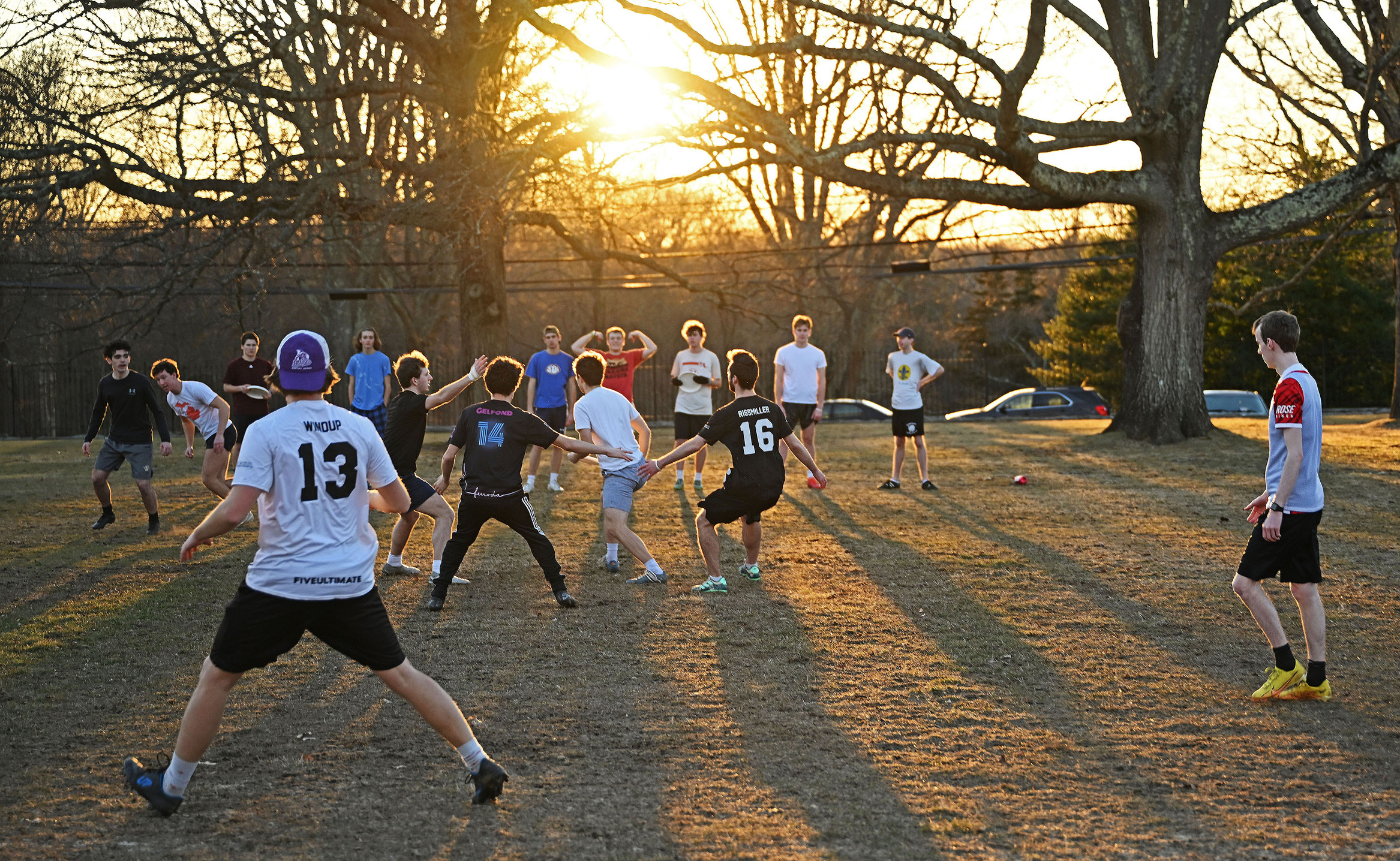 Students play ultimate frisbee on Harkness Green before sunset