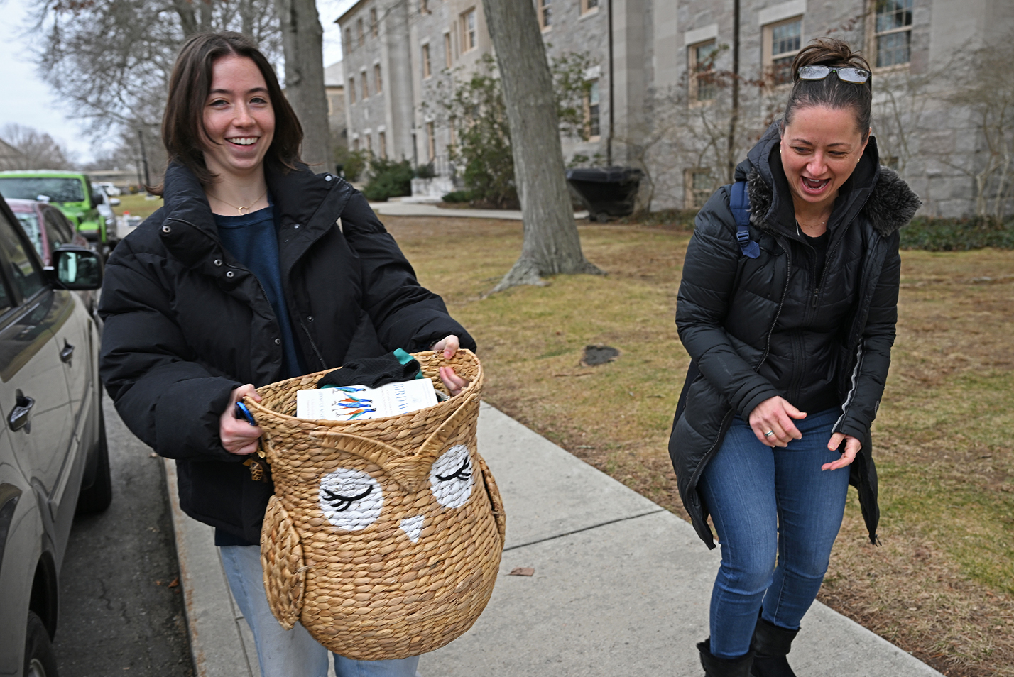 A student and her mom carry personal belongings into a dorm.
