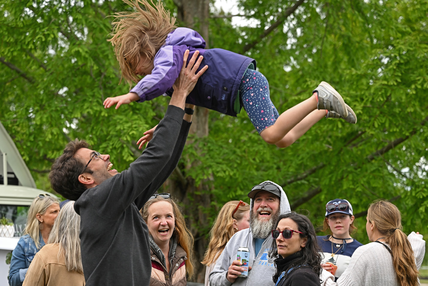 A happy alum parent tosses their child in the air during Reunion.