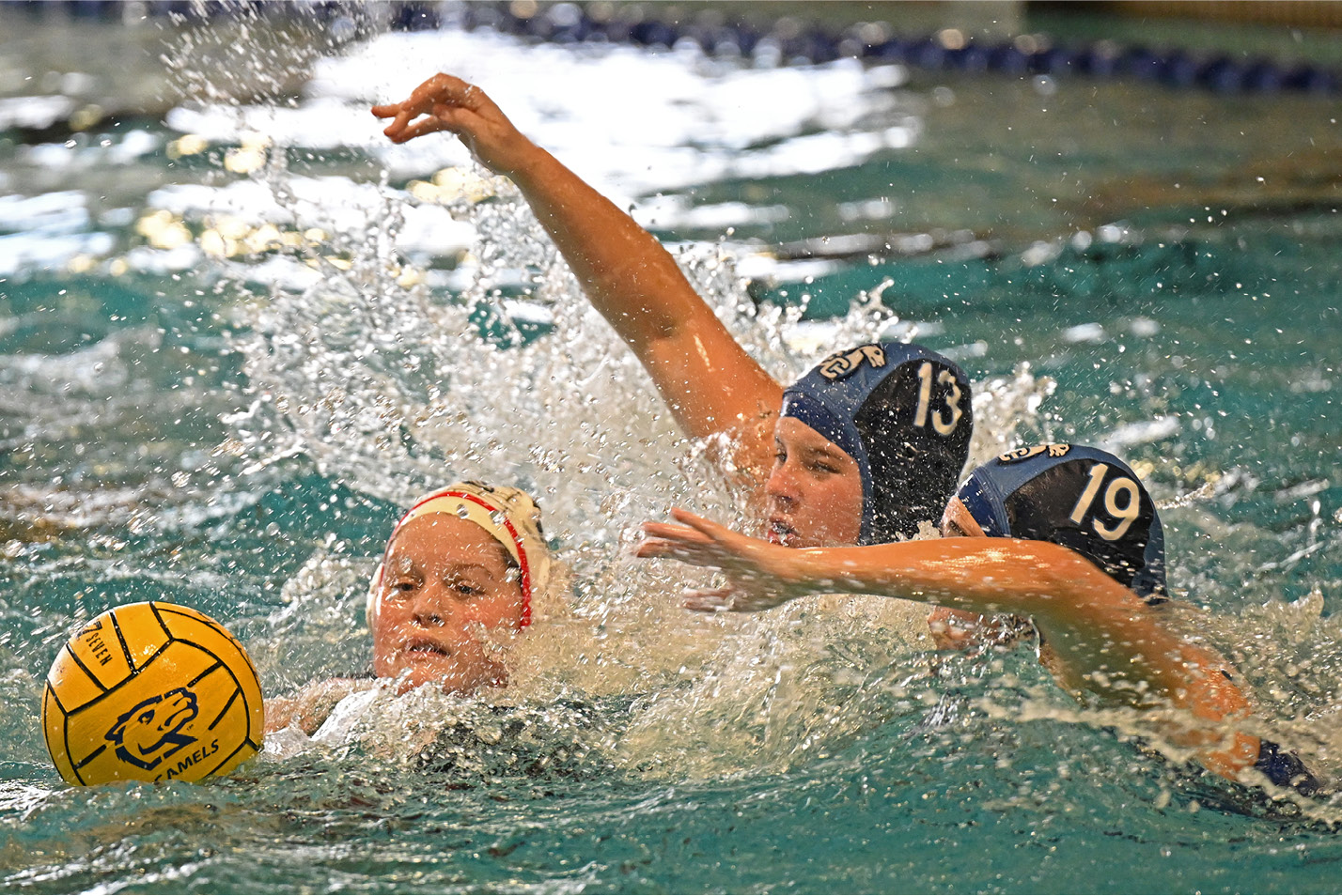 Women's water polo players chase the ball.