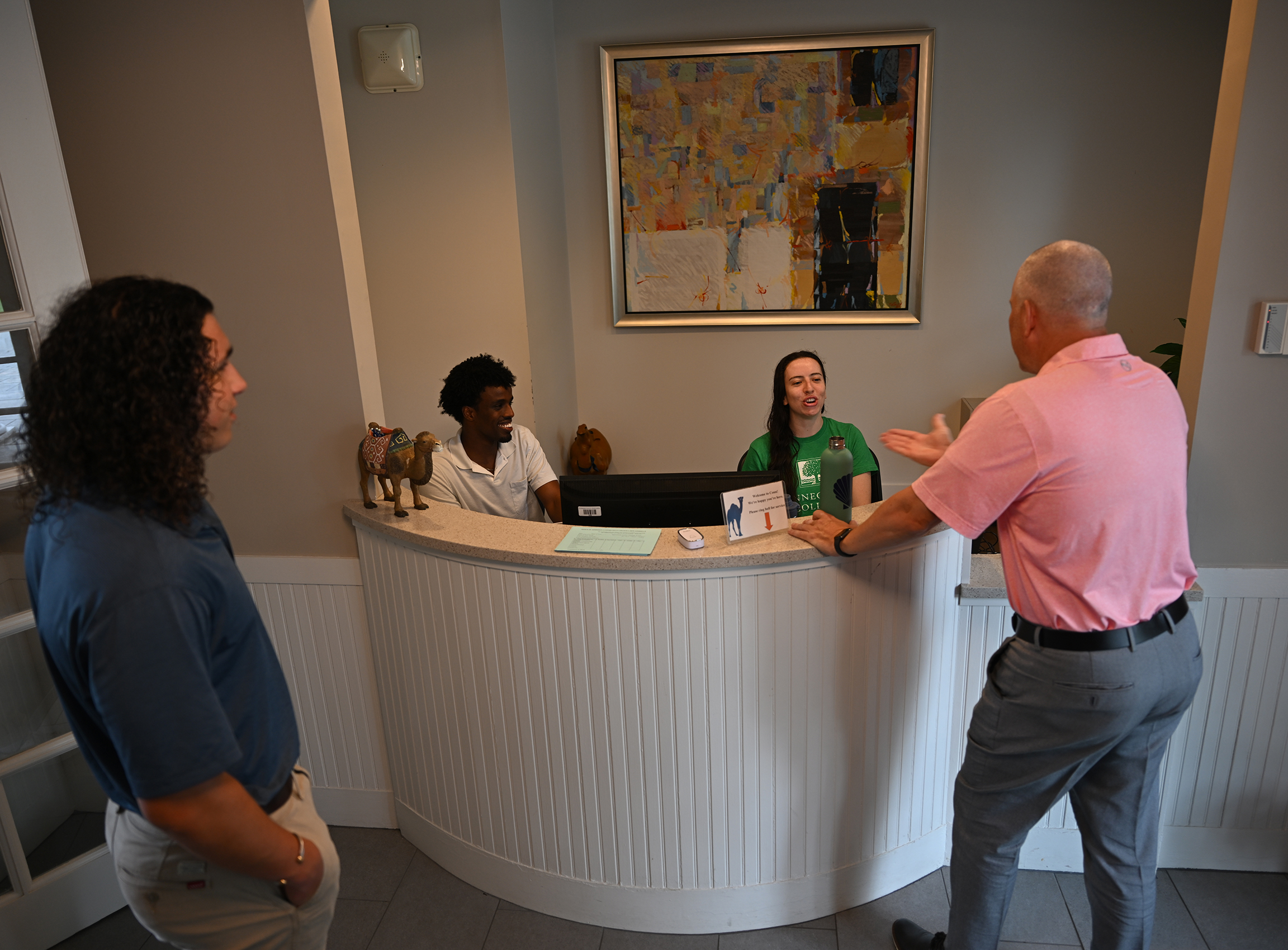 Dean of admission speaks with student workers at reception desk