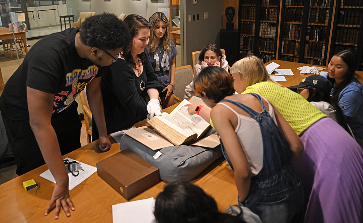Students gather around archivist showing off antique book