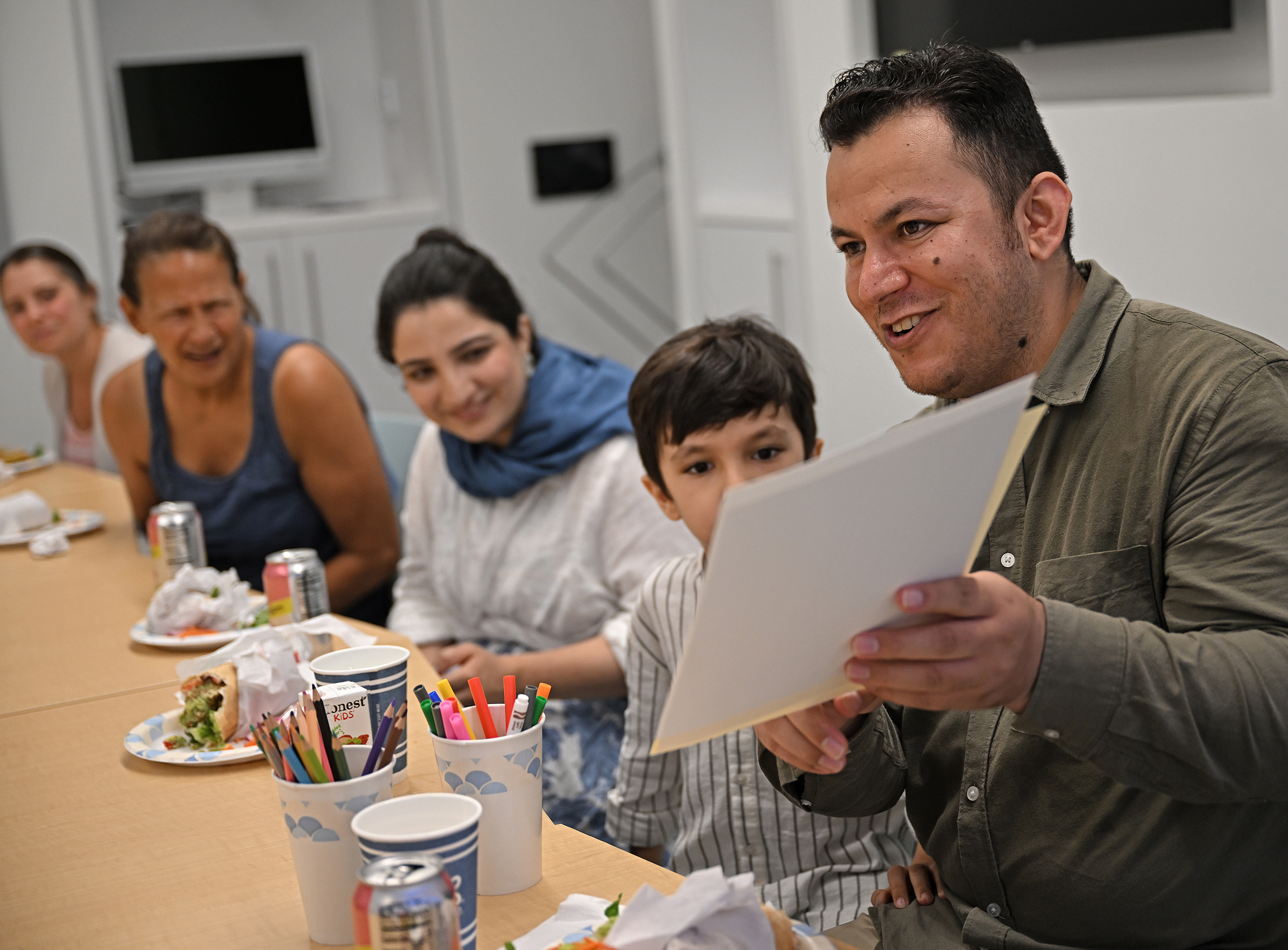 a professor holds papers while speaking to a group of people