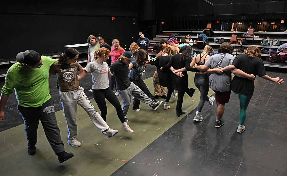 Cast sings and dances in big X formation in middle of stage