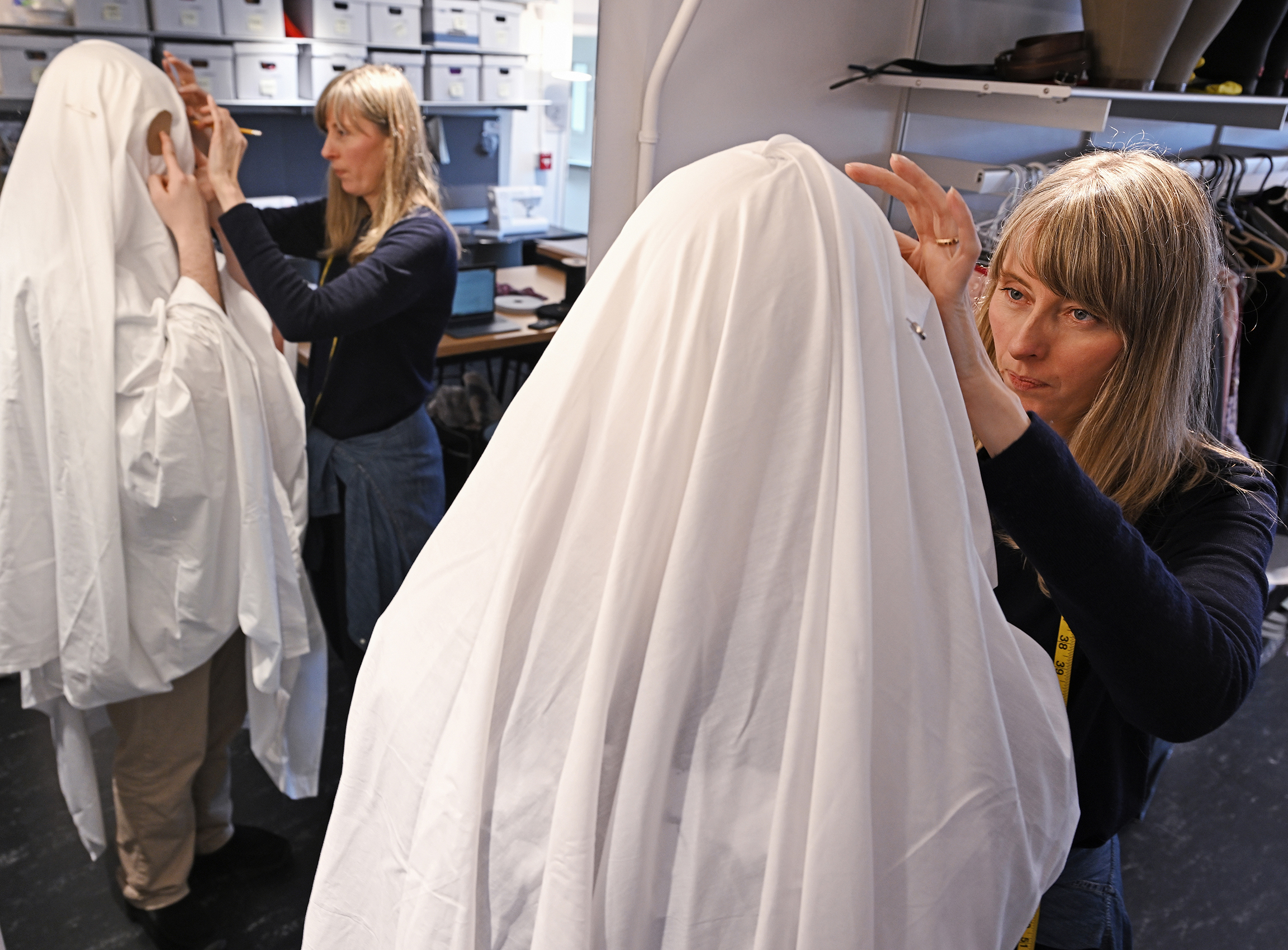 costumer fits actor in ghost sheet costume