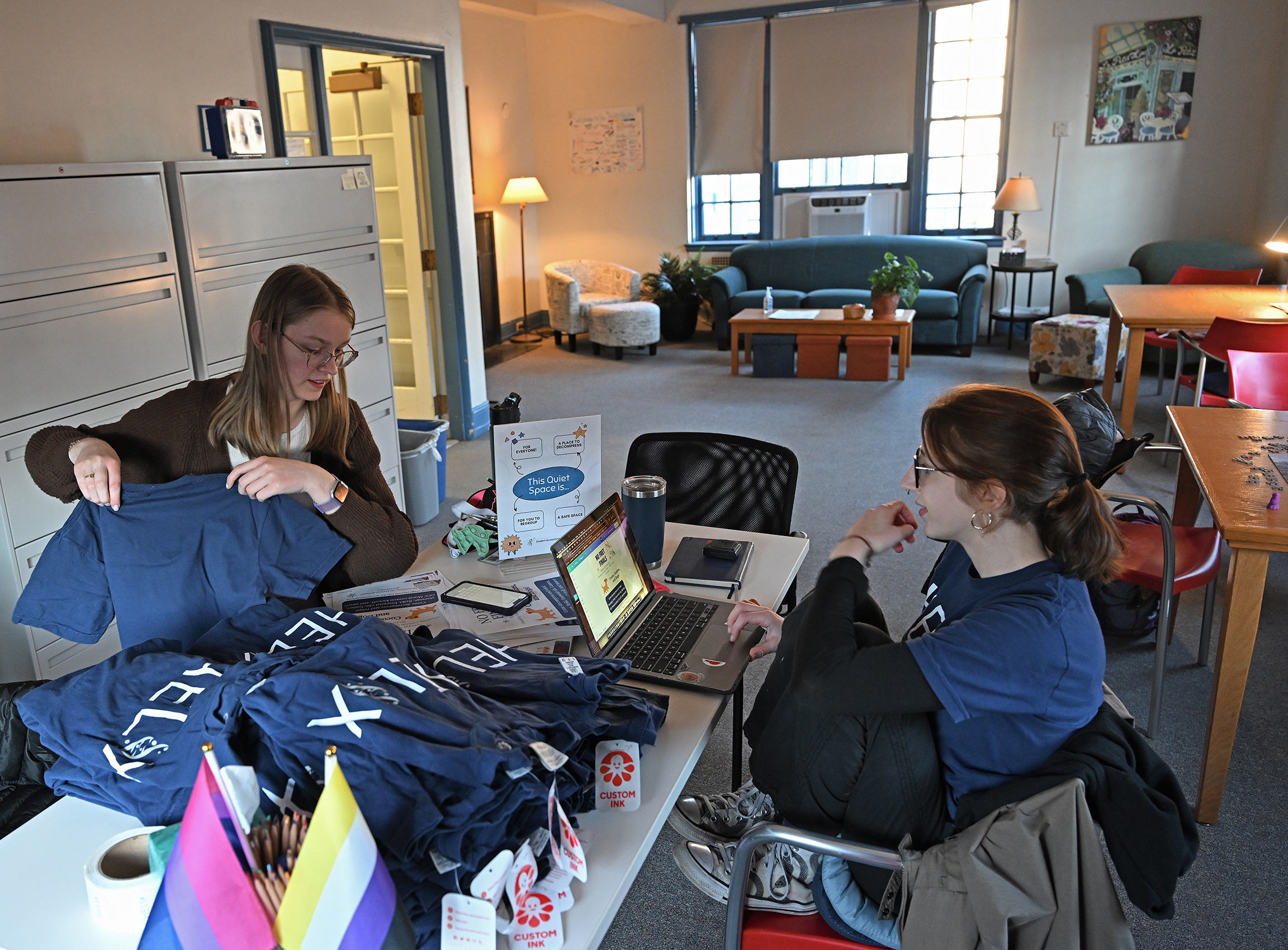 Two students at a table inventory t-shirts.