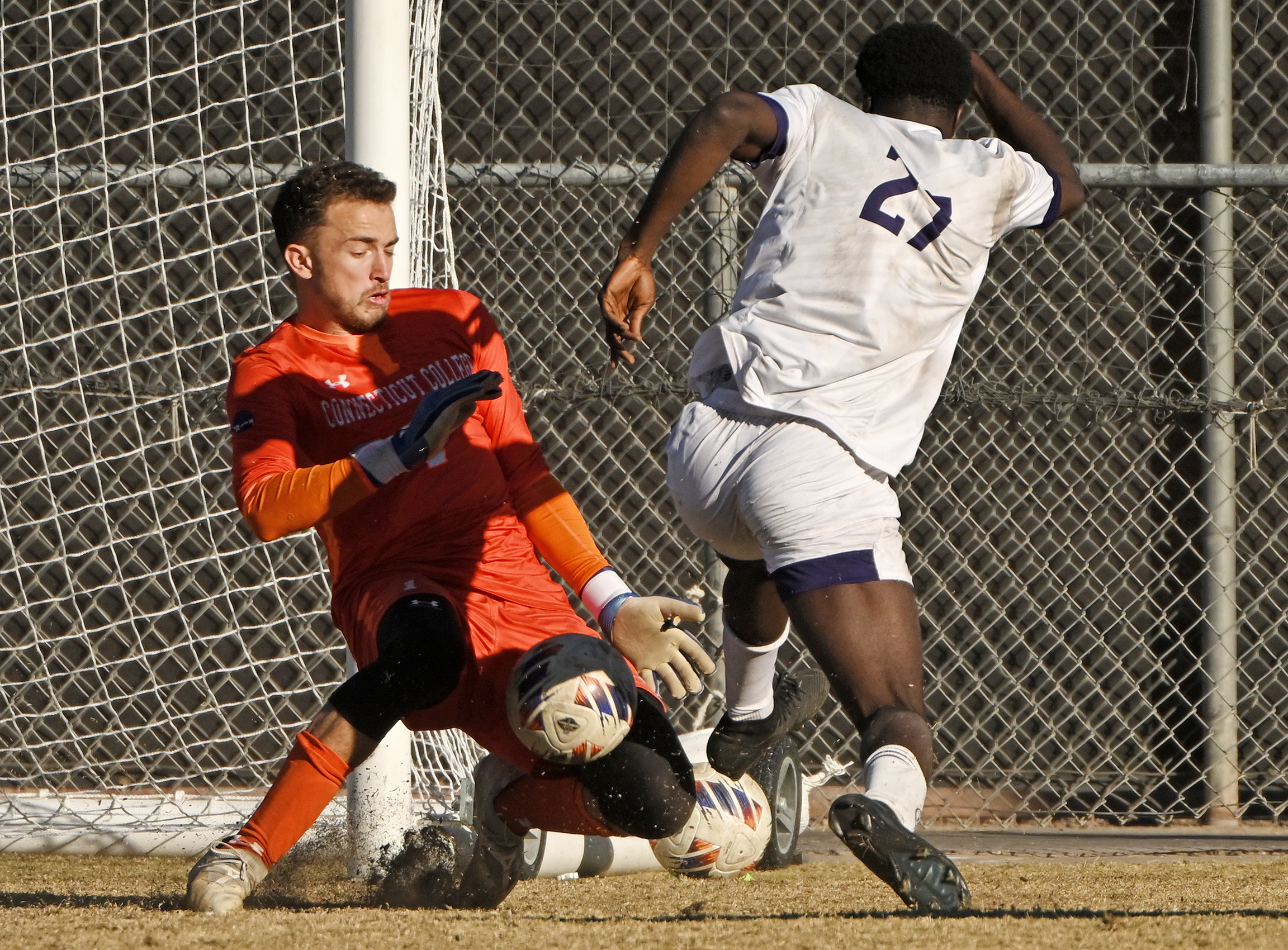 A soccer goalie makes a save against an opponent.