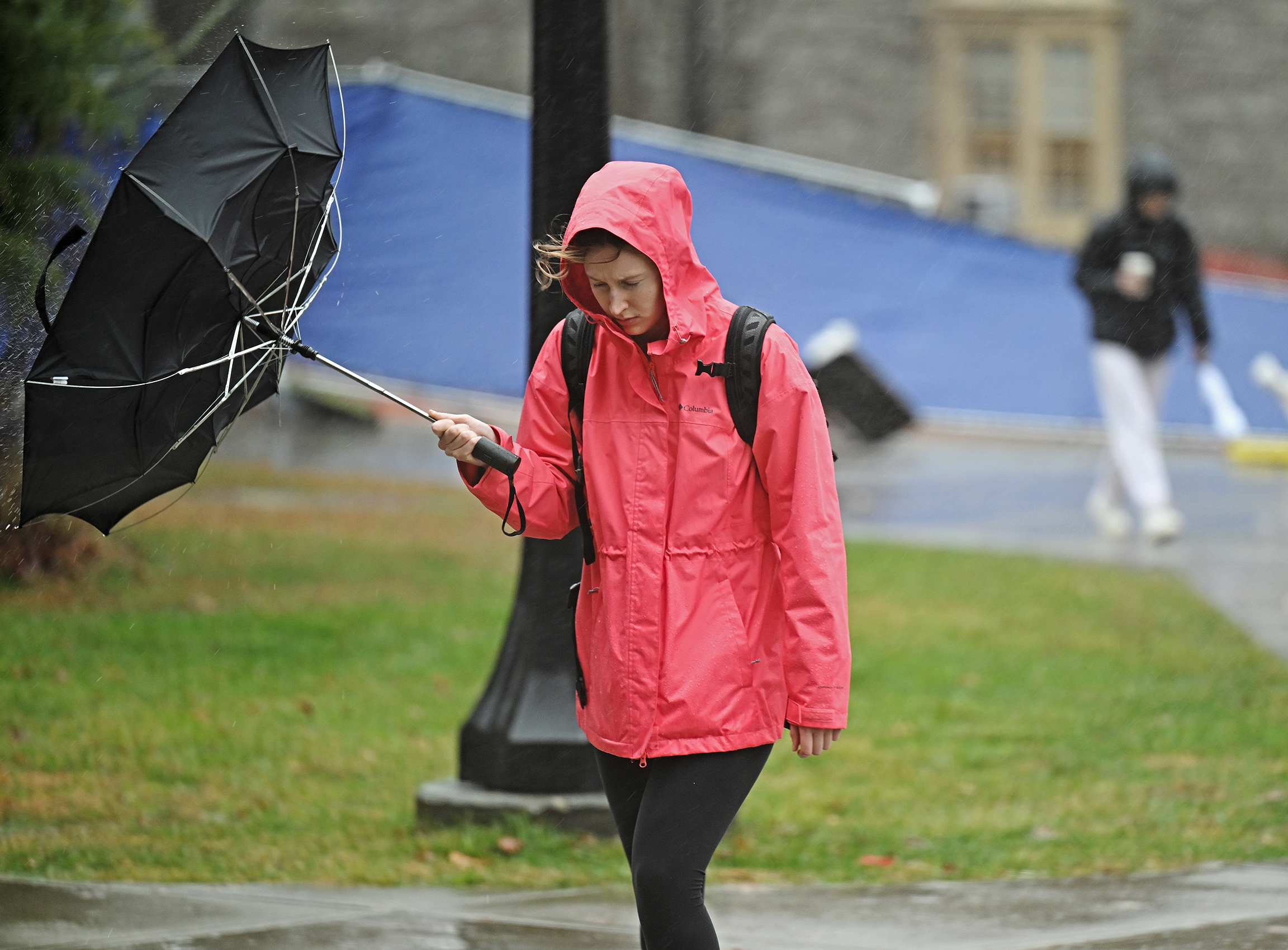 A student deals with an inverted umbrella on a rainy afternoon.