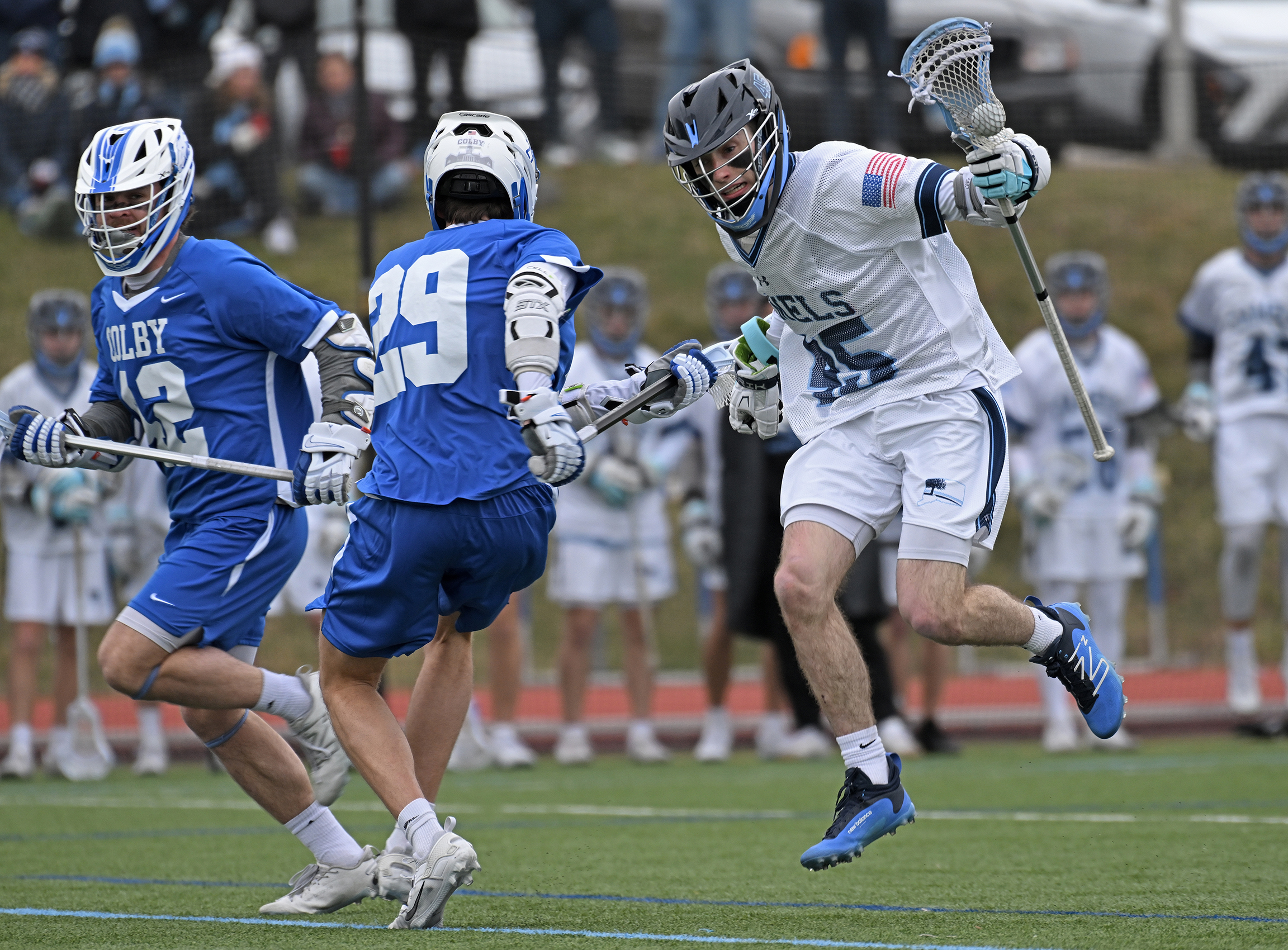 lacrosse player jumps in the air to evade a defender