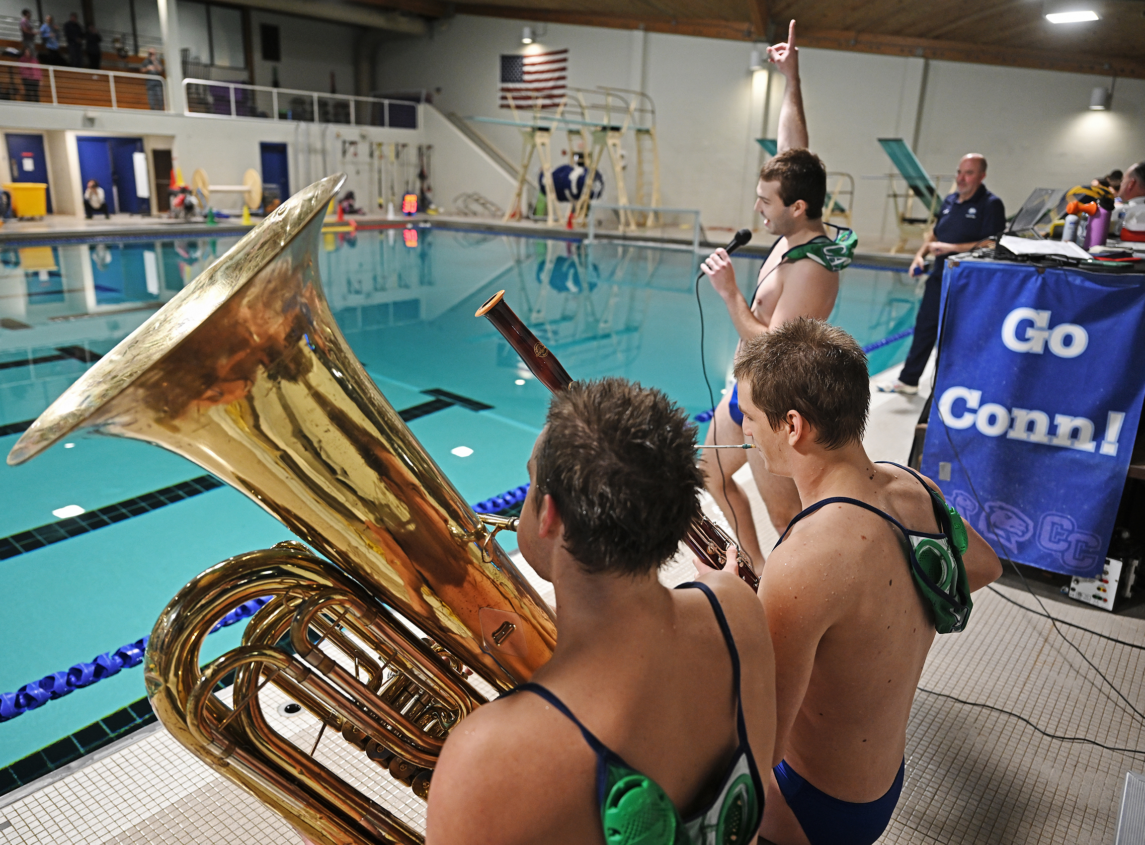 A water polo player sings the National Anthem accompanied by teammates on tuba and oboe.
