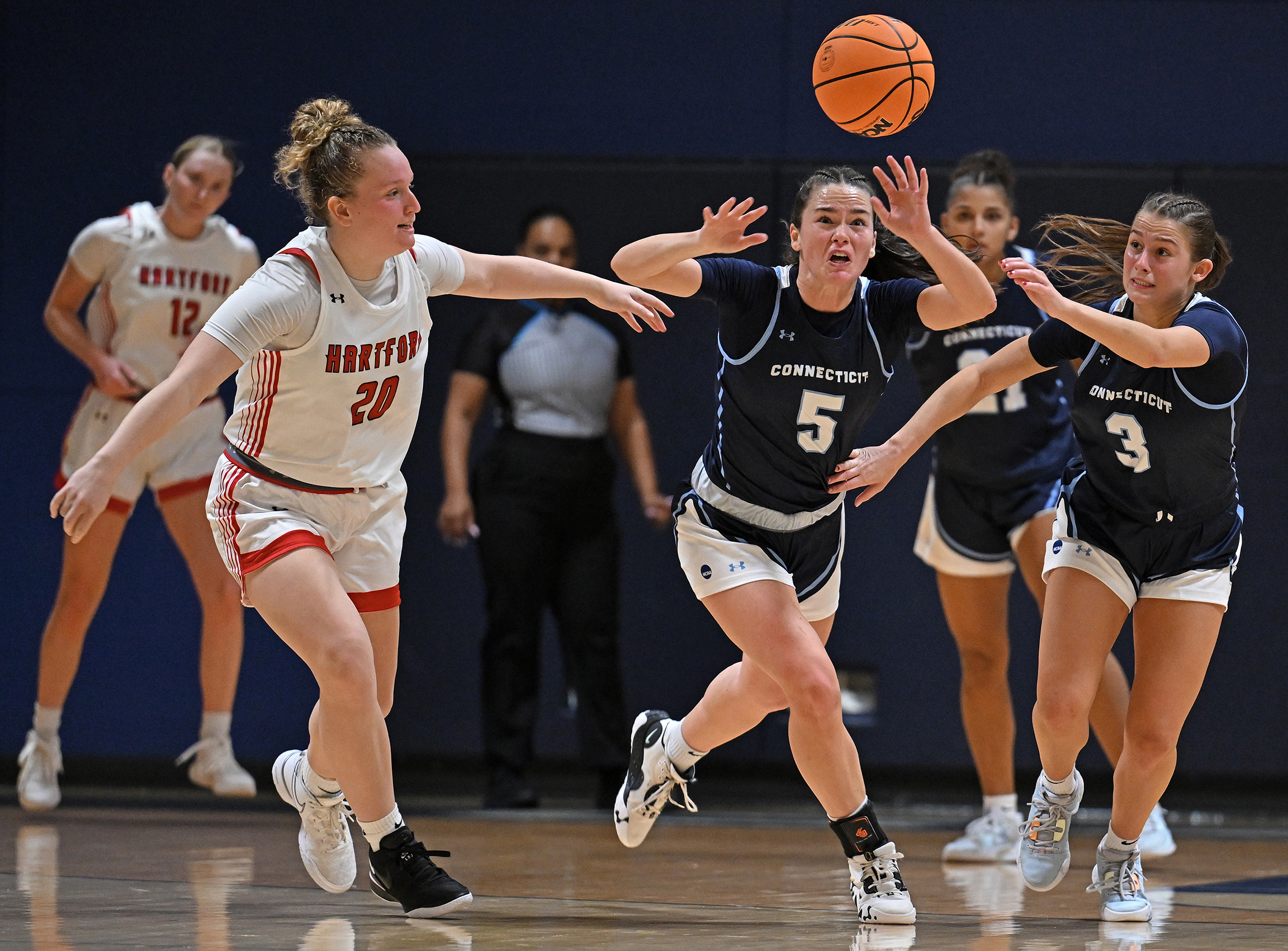 A basketball player chases a loose ball over her head after knocking it away from her opponent.