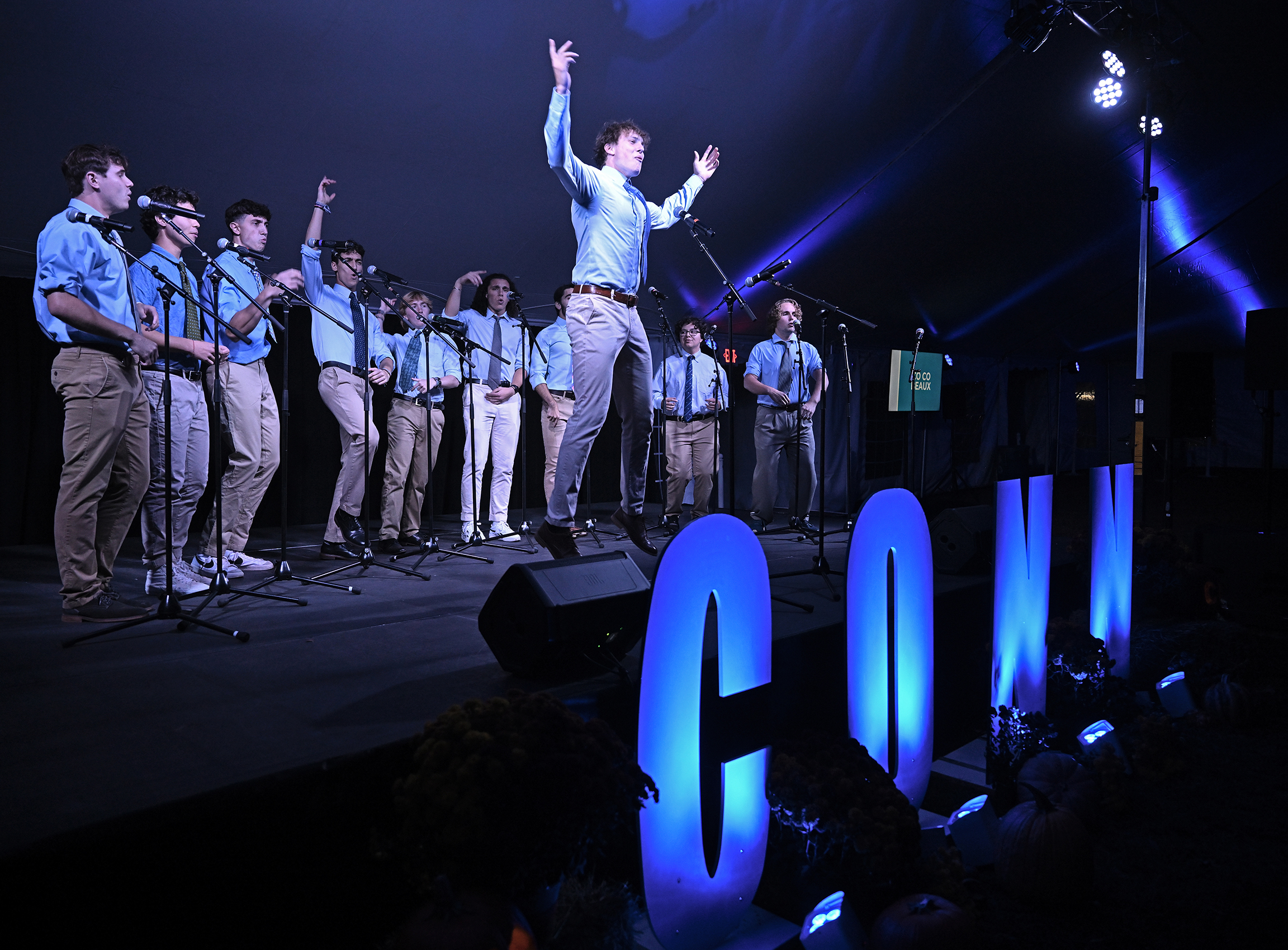 A member of an a cappella group jumps in the air during a performance.